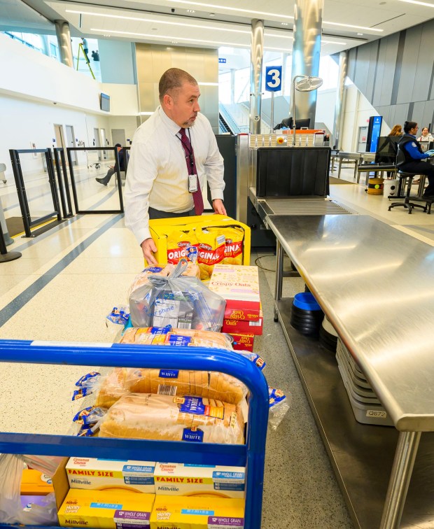 Transportation security manager Brian Weaver loads donated items onto a conveyer belt to be scanned by Transportation Security Administration workers during a Fill the Bus donation drive Thursday, March 19, 2026, at Lehigh Valley International Airport. More than 20 carts were filled with donated paper products; toiletries, diapers and other baby products; gift cards; and nonperishable foods and beverages for TSA and Federal Aviation Administration workers at the airport who aren't being paid during the partial federal government shutdown. (April Gamiz/The Morning Call)