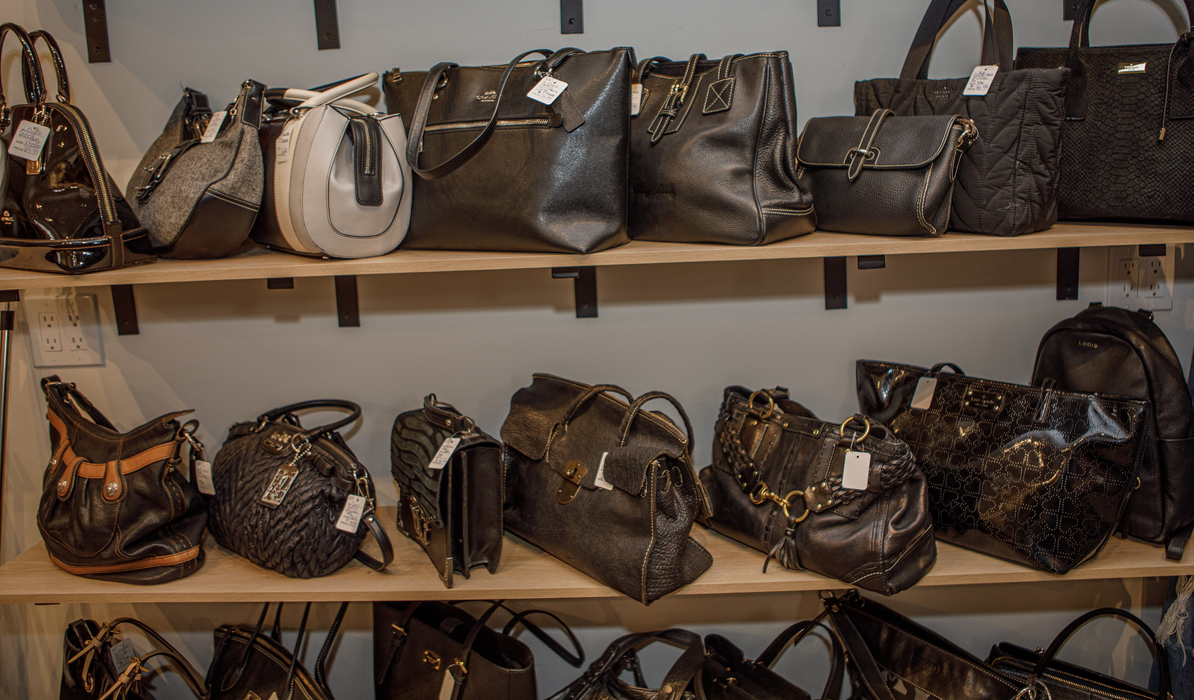 Handbags on display inside Indulge Designer Resale Boutique poses inside...