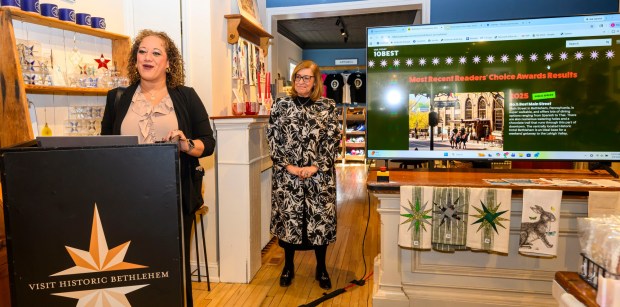 Marci Martinez-Howey, board chair of the Bethlehem Chamber of Commerce, speaks as Kelly Ronalds, general manager of Historic Hotel Bethlehem, watches Monday, March 9, 2026, during a news conference at Schropp Dry Goods Shoppe in Bethlehem unveiling that Main Street in Bethlehem was nominated in USA Today's 10Best Main Street competition for 2026. It won in 2025. The news conference also introduced the Our Star Shines All Year Round marketing campaign to encourage travelers to visit the city. (April Gamiz/The Morning Call)