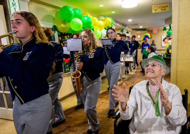 Margie, a resident at Arden Courts Old Orchard memory care community in Bethlehem Township, claps as the Notre Dame-Green Pond Crusaders Band marches past her Tuesday, March 17, 2026, during a St. Patrick's Day celebration at Arden Courts Old Orchard, a memory care community, in Bethlehem Township. (April Gamiz/The Morning Call)