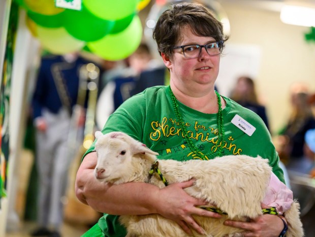 Employee Krista Morgan carries a lamb Tuesday, March 17, 2026, during a St. Patrick's Day celebration at Arden Courts Old Orchard, a memory care community, in Bethlehem Township. (April Gamiz/The Morning Call)