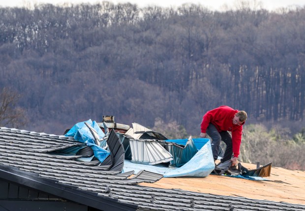 Scott Grub of Advanced Disaster Recovery Inc. inspects a roof Tuesday, March 17, 2026, on South 12th Street in Allentown after it was damaged by Monday night's strong winds. Storms blew off roofs and downed trees and power lines around the Lehigh Valley, leaving thousands without electricity. (April Gamiz/The Morning Call)