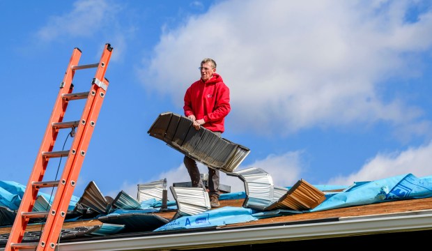 Scott Grub of Advanced Disaster Recovery Inc. inspects a roof Tuesday, March 17, 2026, on South 12th Street in Allentown after it was damaged by Monday night's strong winds. Storms blew off roofs and downed trees and power lines around the Lehigh Valley, leaving thousands without electricity. (April Gamiz/The Morning Call)