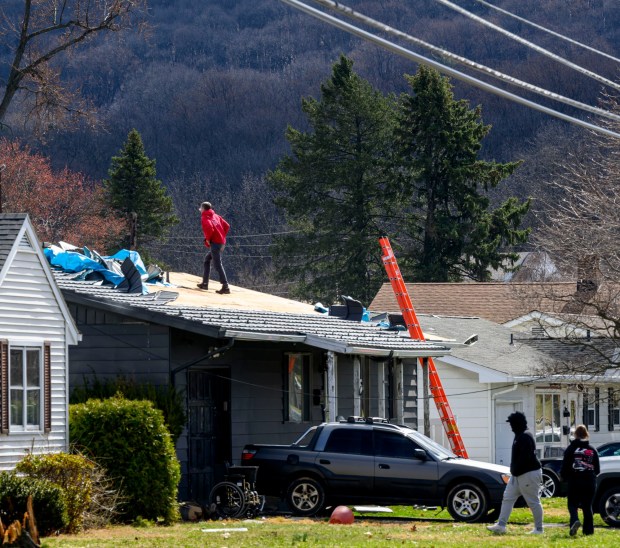 Scott Grub of Advanced Disaster Recovery Inc. inspects a roof Tuesday, March 17, 2026, on South 12th Street in Allentown after it was damaged by Monday night's strong winds. Storms blew off roofs and downed trees and power lines around the Lehigh Valley, leaving thousands without electricity. (April Gamiz/The Morning Call)