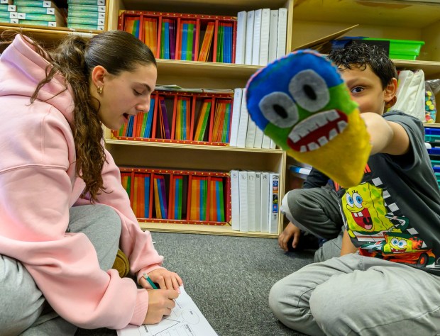 Moravian University student Siria Moretti engages with third graders Julian J. and Yamoussa T. on Monday, March 2, 2026, at William Penn Elementary School in Bethlehem, where Moravian University students are running a story workshop for third graders. The university students, part of Moravian's art and child development education course, are using puppets to engage the third graders in shaping characters and themes for original children's books. (April Gamiz/The Morning Call)