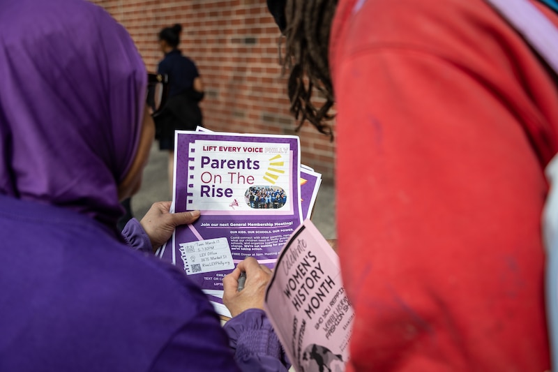 A photograph of two people looking at a colorful flyer.
