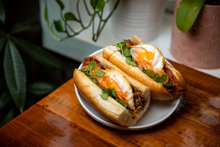 Banh Mi Op La, two crispy sunny eggs, bacon, sausage patties, house pickles, herbs, eggplant pate, and b. aioli on a baguette at The Breakfast Den.