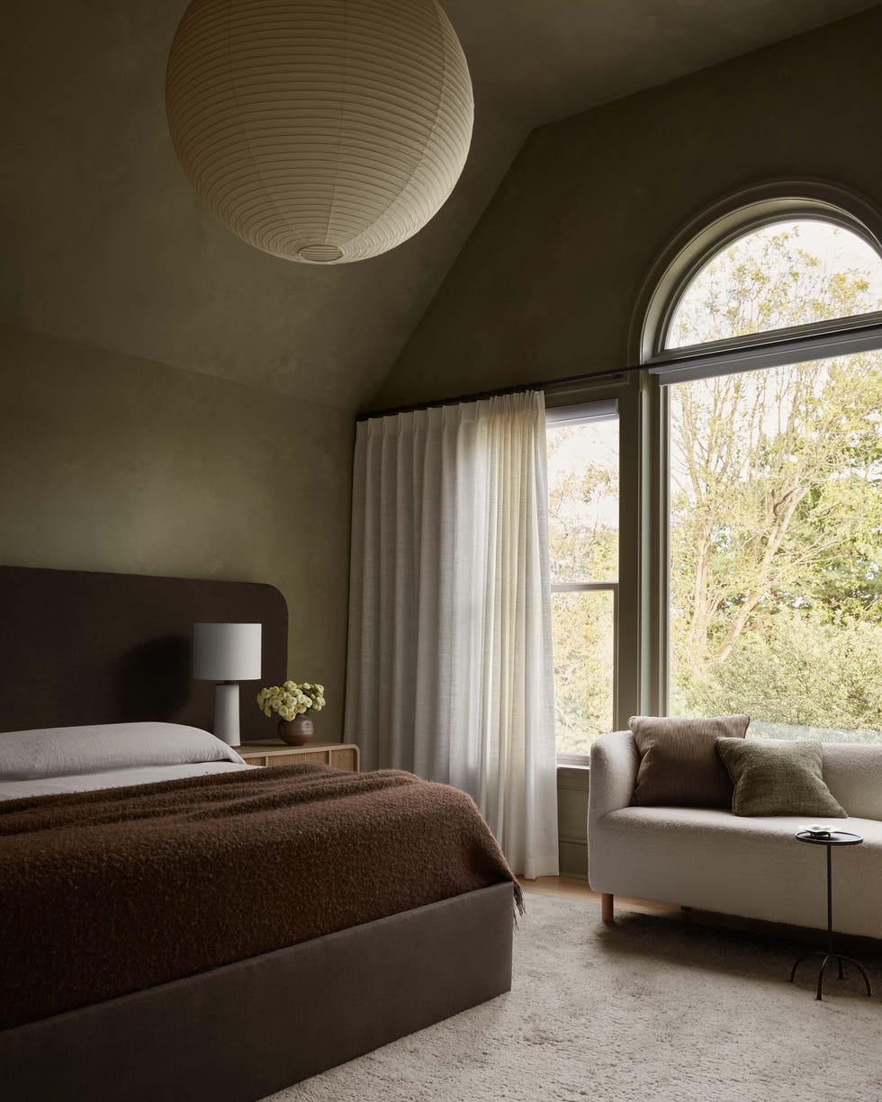 Cozy bedroom with a bed, lamp, and window view.