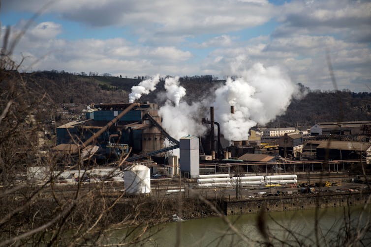 A riverside steel plant emits smoke from its smokestacks.