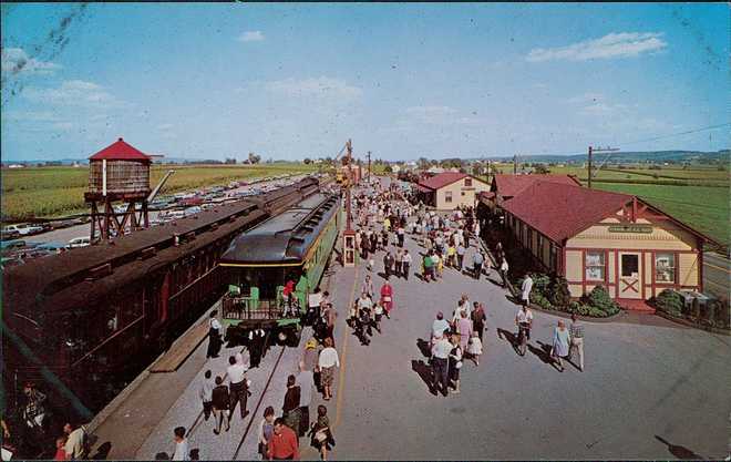 Strasburg Rail Road Postcard depicting a crowd at the main terminal of the Strasburg Rail Road, East Strasburg, Pennsylvania, United States, 1960. The scene includes a vintage train and water tower with people walking along the platform. (Photo by Smith Collection/Gado/Getty Images)