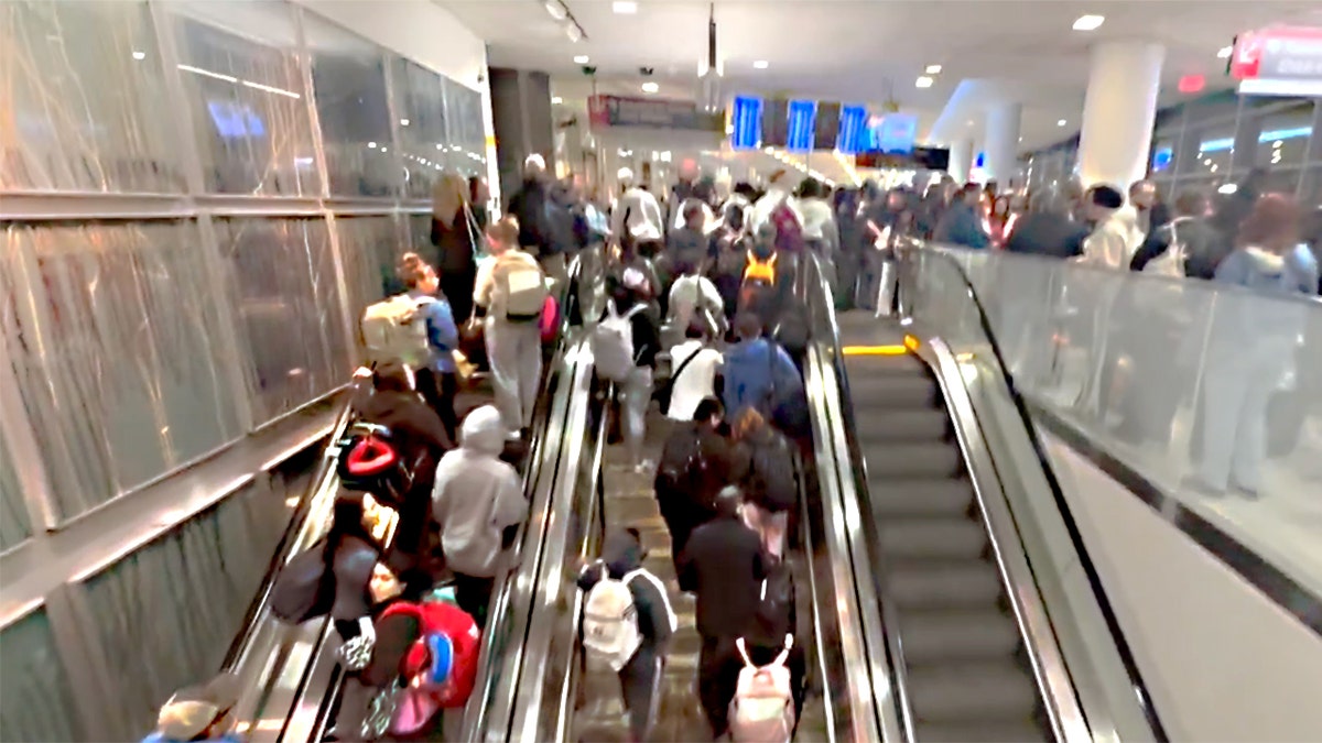 Travelers stand on stairway waiting to enter TSA