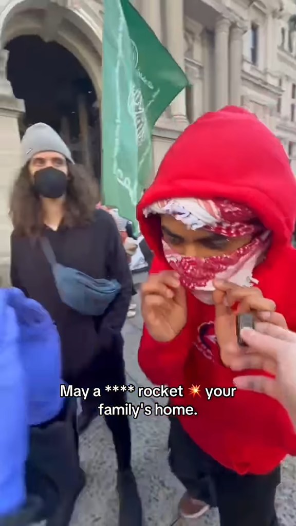 Pro-Iranian Philadelphia protestor in a red hoodie and keffiyeh holding a lighter.