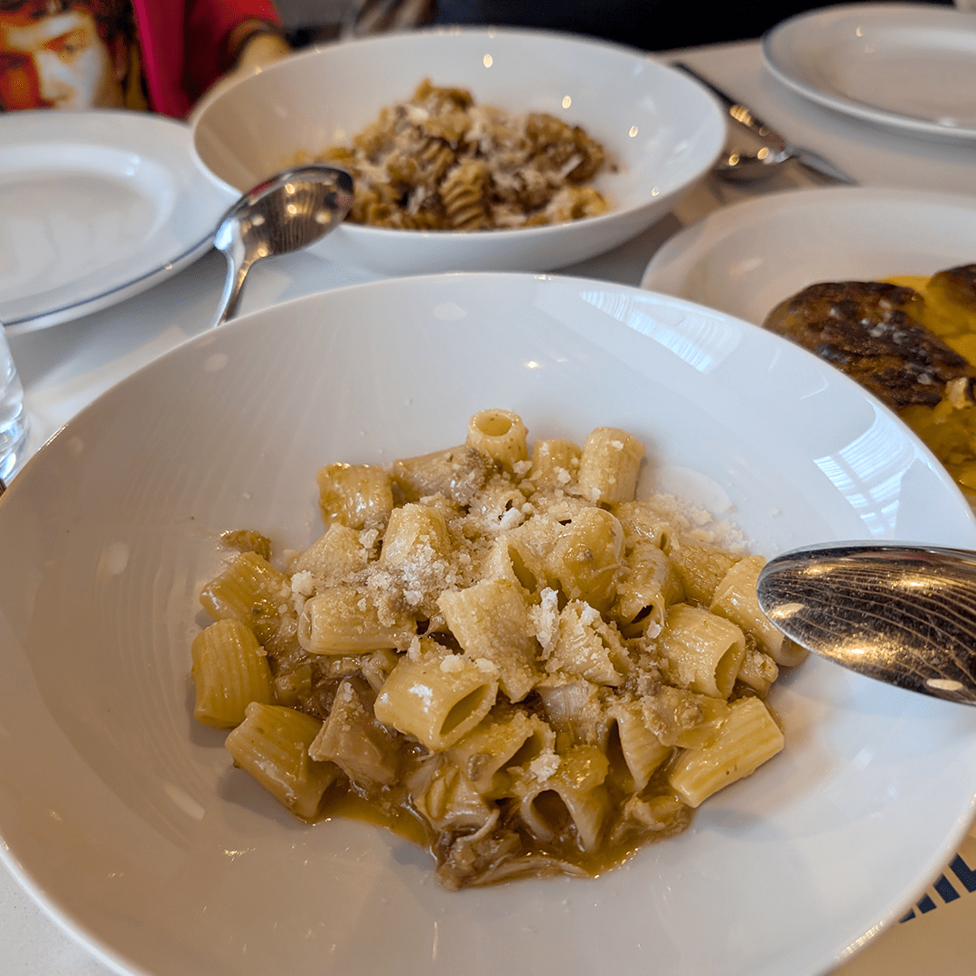 A plate of rigatoni with sauce and chicken on a white plate.