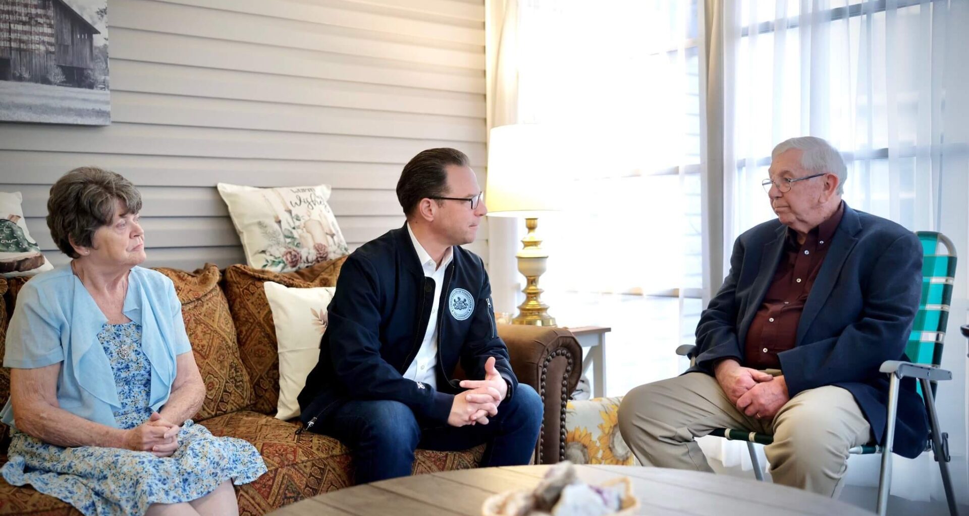 Pennsylvania Governor Josh Shapiro seated, speaking with a family at a manufactured housing community in Berks County