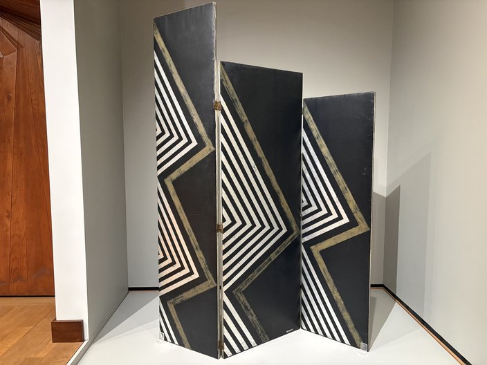 Three-panel black screen with zig-zagging white and gold lines