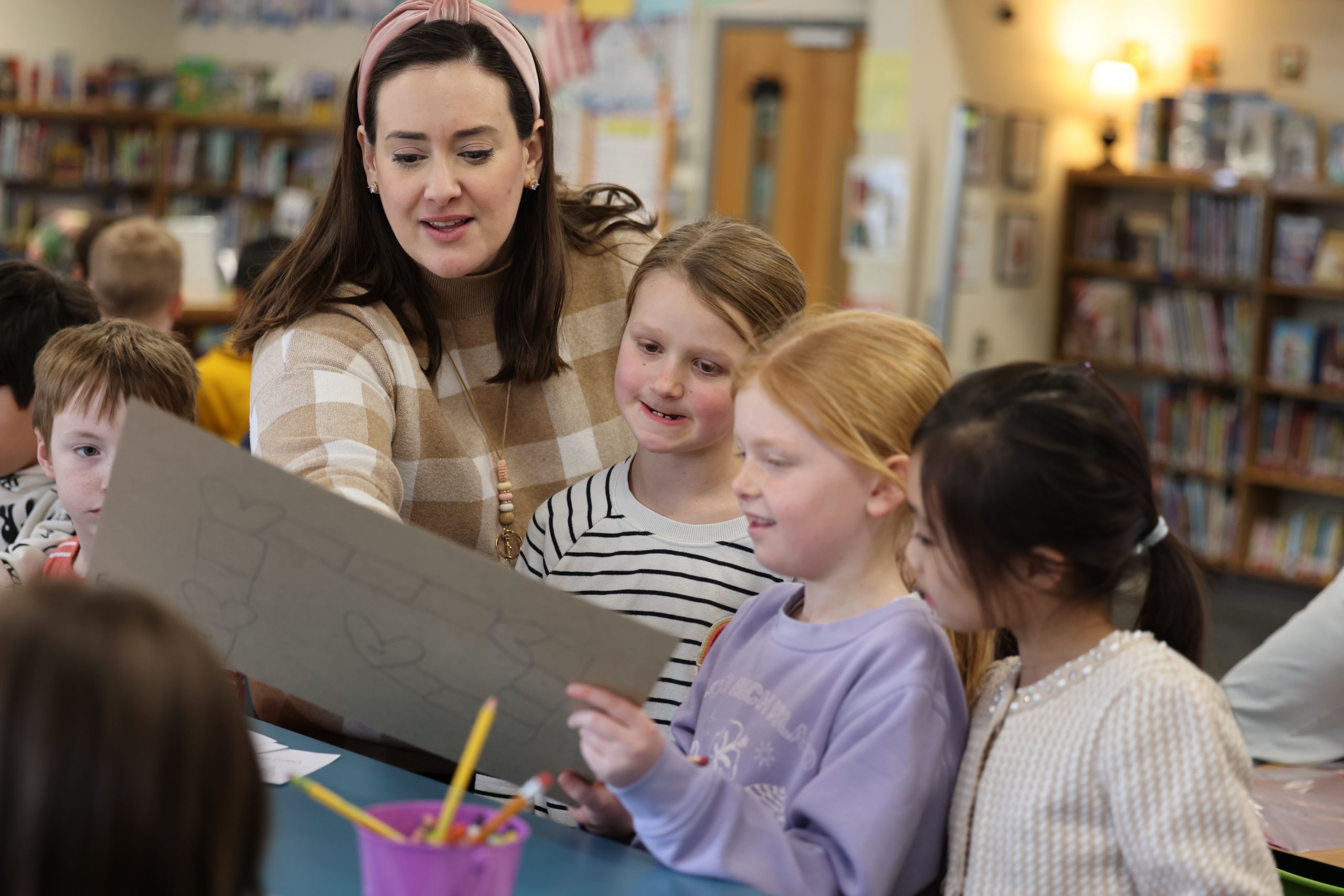 teacher points to game board while students look on