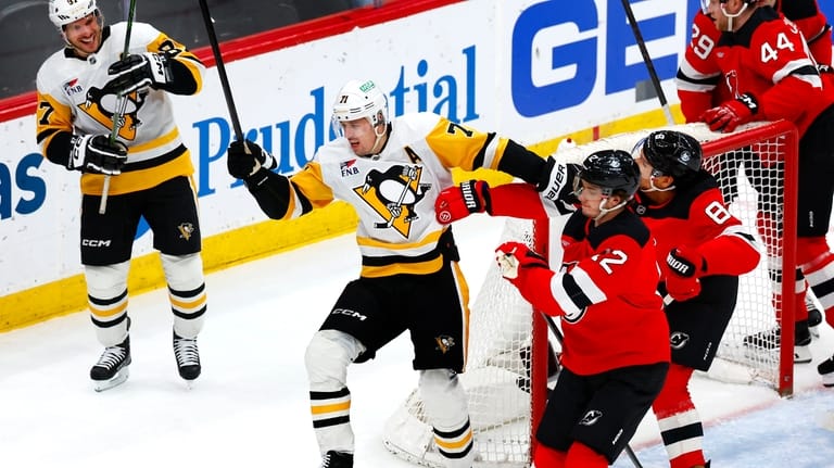 Pittsburgh Penguins' Sidney Crosby, left, watches the reaction of center...