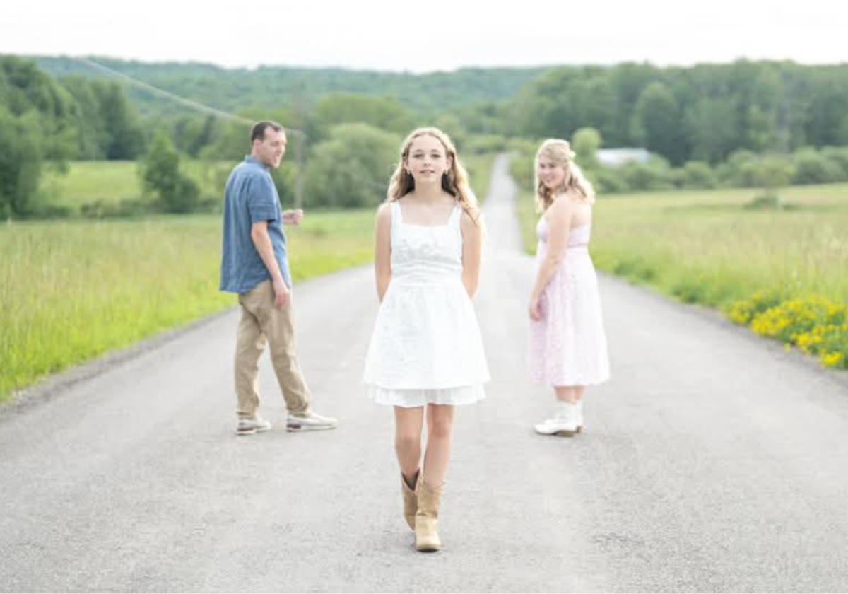 Beautiful photo of girl on road with parents in background. Photo by Evan Grace Portraits in Erie PA