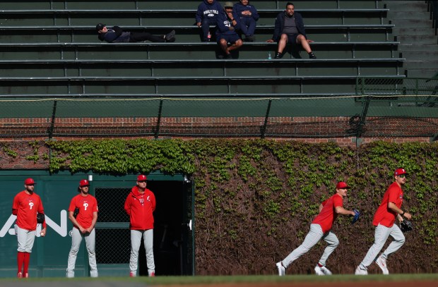 Phillies pitchers shag batting practice balls as Wrigley Field workers watch from the bleachers before a Cubs-Phillies game on April 22, 2026, in Chicago. (John J. Kim/Chicago Tribune)