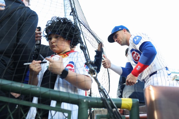 Cubs third baseman Alex Bregman, right, gives a thumbs up to a fan while signing autographs before a game against the Phillies at Wrigley Field on April 22, 2026, in Chicago. (John J. Kim/Chicago Tribune)