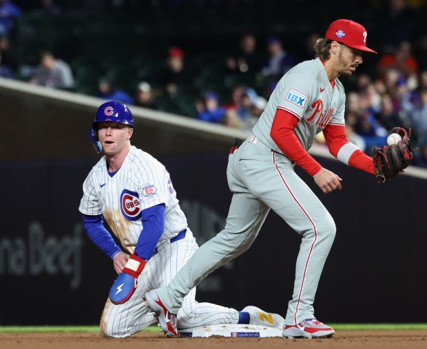 Cubs center fielder Pete Crow-Armstrong, left, rises after stealing second base ahead of Phillies second baseman Bryson Stott in the eighth inning at Wrigley Field on April 22, 2026, in Chicago. (John J. Kim/Chicago Tribune)