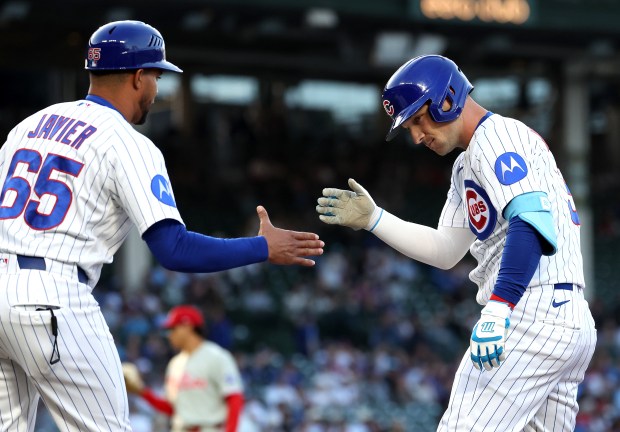 Chicago Cubs designated hitter Alex Bregman (right) is congratulated by first base coach Jose Javier (65) after Bregman singled in the first inning of a game against the Philadelphia Phillies at Wrigley Field in Chicago on April 21, 2026. (Chris Sweda/Chicago Tribune)