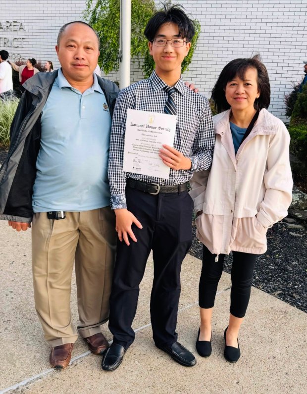Loc Bui Phạm, with his mother, Hong Phạm, and father, Phuc Bui, holds his National Honor Society certificate of membership.