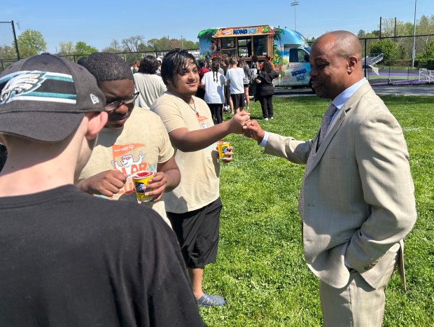 Upper Darby High School Principal Dr. Craig Parkinson speaks with Super Seniors Christopher Galloway, Justin Smith and Pakeer Rahman while they enjoy water ice at the April Showers event. (PETE BANNAN-DAILY TIMES)