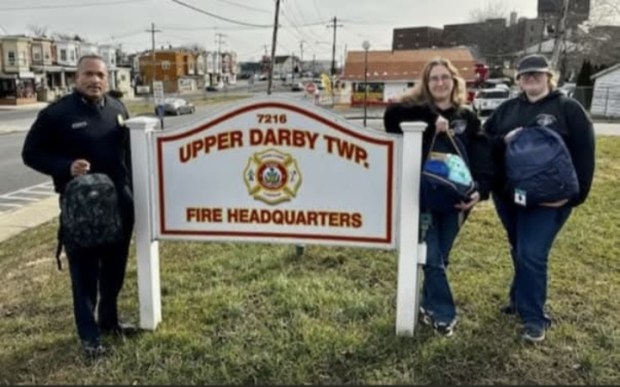 Past Upper Darby Fire Chief Derrick Sawyer, left, receives one of the comfort bags from Upper Darby Marine Corps League Auxiliary members Erika Krautheim, second from right, and Rebecca Dengel a few years ago. (COURTESY OF ERIKA KRAUTHEIM)