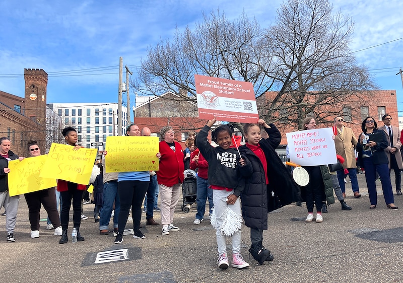 Children and adults hold signs.