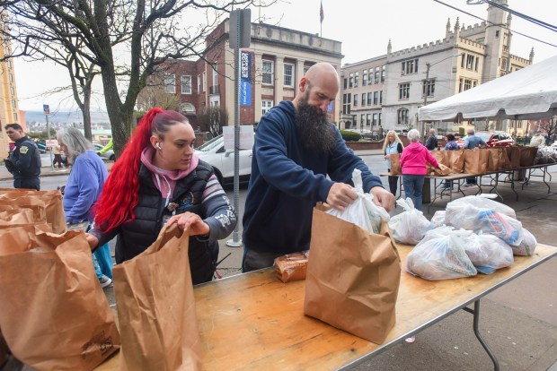 Catherine McAauley Center coordinator Yani Diaz and volunteer Brian Nasko put out bags of food during the Family to Family Easter Giveaway on N. Washington Ave. in Scranton Wednesday, April 1, 2026. (SEAN MCKEAG / STAFF PHOTOGRAPHER)
