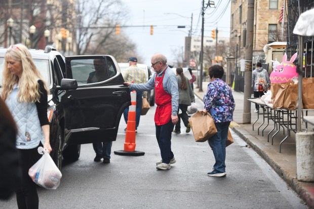 Volunteers load up vehicles with bags of food during the Family to Family Easter Giveaway on N. Washington Ave. in Scranton Wednesday, April 1, 2026. (SEAN MCKEAG / STAFF PHOTOGRAPHER)