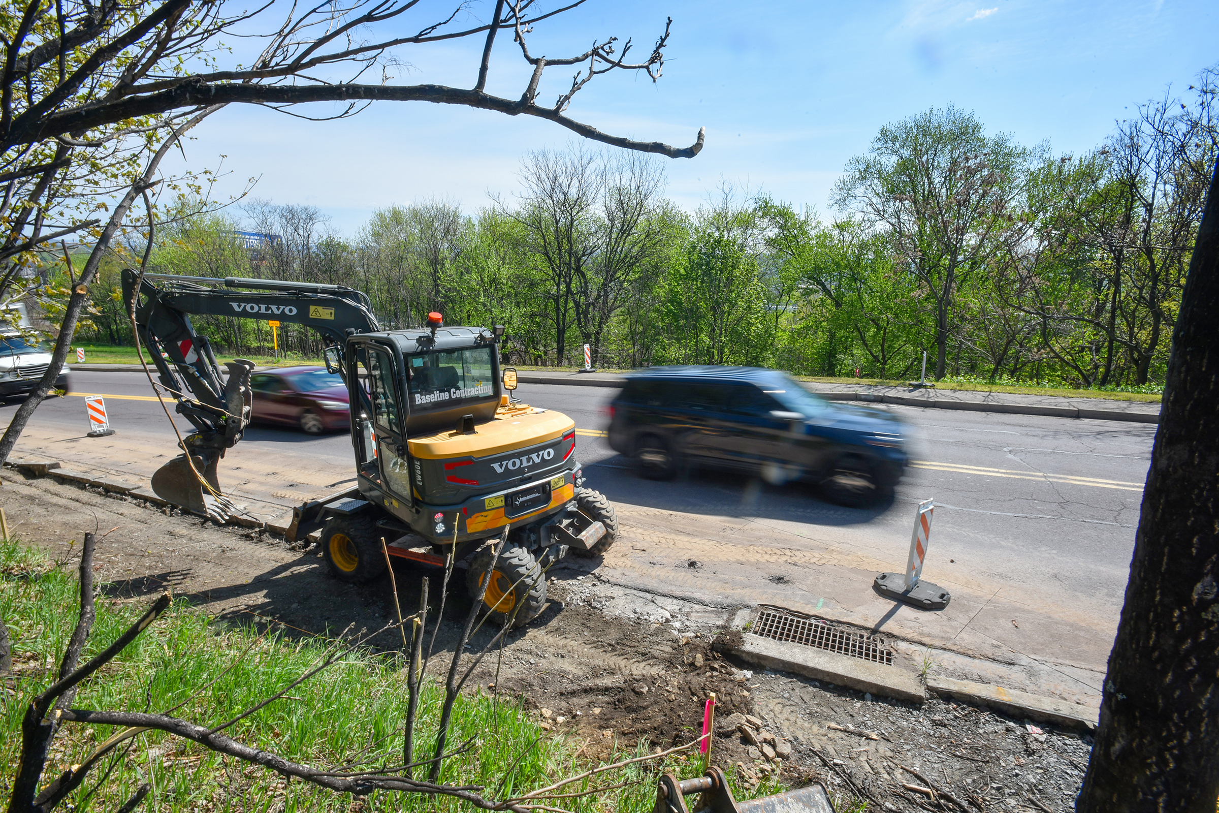 A worker from Baseline Contracting operates an excavator as vehicles...