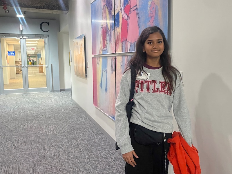 A photograph of a middle school student standing for a photo in a hallway.
