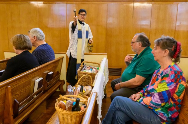 Rev. Giuseppe Esposito sprinkles holy water on prepared Easter baskets of Jim and Sandy Yackanicz of Bethlehem on Saturday, April 4, 2026, during a blessing of the food baskets on Holy Saturday at St. Anne Catholic Church in Bethlehem. (April Gamiz/The Morning Call)