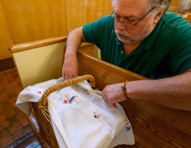 Jim Yackanicz of Bethlehem covers one of his Easter baskets by a cloth that was embroidered by his great-great grandmother Saturday, April 4, 2026, during a blessing of the food baskets on Holy Saturday at St. Anne Catholic Church in Bethlehem. (April Gamiz/The Morning Call)