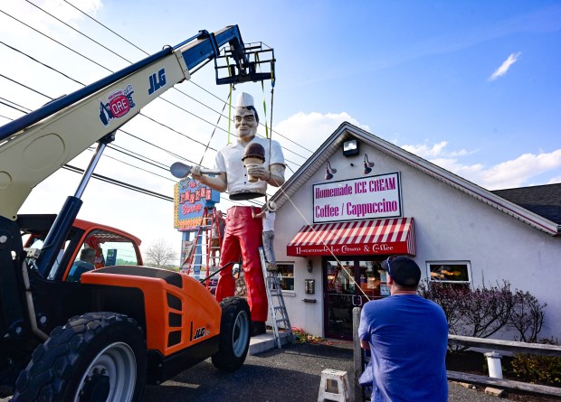 Roadside artist Mark Cline guides the top on to the bottom of the Giant Chip statue Thursday, April 16, 2026, at Inside Scoop in Coopersburg. Chris Elston assists by holding the rope to adjust and keep the pieces lined up. The popular, 25-foot-high statue was toppled by high winds in February. Cline, who built the statue, was on site Thursday to repair it. (Monica Cabrera / The Morning Call)