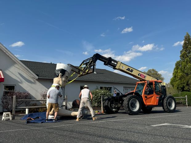 A lift prepares to hoist the repaired top half of Giant Chip back in place Thursday, April 16, 2026, at Inside Scoop in Coopersburg. The popular, 25-foot-high statue was toppled by high winds in February. Roadside artist Mark Cline, who built the statue, was on site Thursday to repair it. (Graysen Golter / The Morning Call)