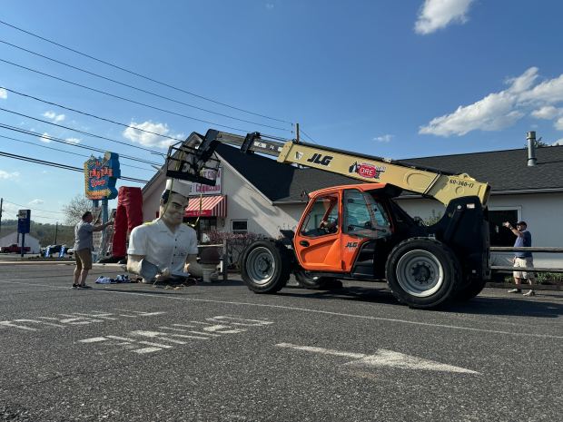 A lift prepares to hoist the repaired top half of Giant Chip back in place Thursday, April 16, 2026, at Inside Scoop in Coopersburg. The popular, 25-foot-high statue was toppled by high winds in February. Roadside artist Mark Cline, who built the statue, was on site Thursday to repair it. (Graysen Golter / The Morning Call)