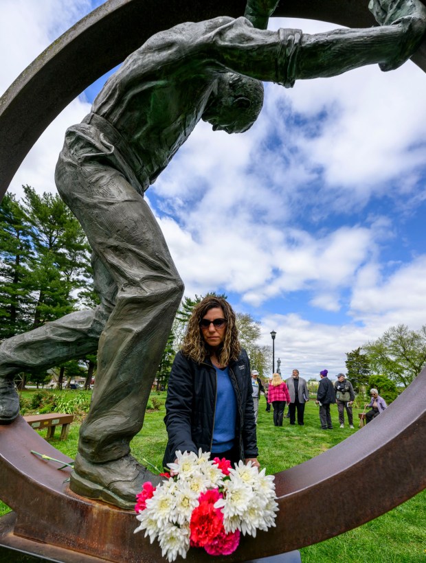 During the 35th annual Lehigh Valley Workers' Memorial Day ceremony Sunday, April 26, 2026, at the Bethlehem Rose Garden, Kim McNair of Nazareth places a carnation on the bronze Workers' Memorial sculpture in memory of her father, John Stefanio, an employee of FMSC of Bethlehem who died while repairing a pressurized pump that burst at Newstech Pa. The ceremony remembered one of the area's bloodiest workplace tragedies, when when two gunmen walked into the First National Bank of Bath and shot five people June 6, 1986, killing three immediately, and a fourth who died years later. Three names will be added this year to the Lehigh Valley Workers' Memorial list, which includes roughly 4,400 workplace facilities since before the Civil War. Added this year are April Lubenetski, 51, who died May 19, 2025, after suffering from occupational cancer as a result of her employment as an Emmaus and Lehigh Township volunteer firefighter; Steven Gill, 36, who died May 21, 2025, when he was hit by an excavator in Weisenberg Township; and James Akins, 57, who died July 29, 2025, after suffering a medical event while installing solar panels on a roof in Allen Township.(April Gamiz/The Morning Call)