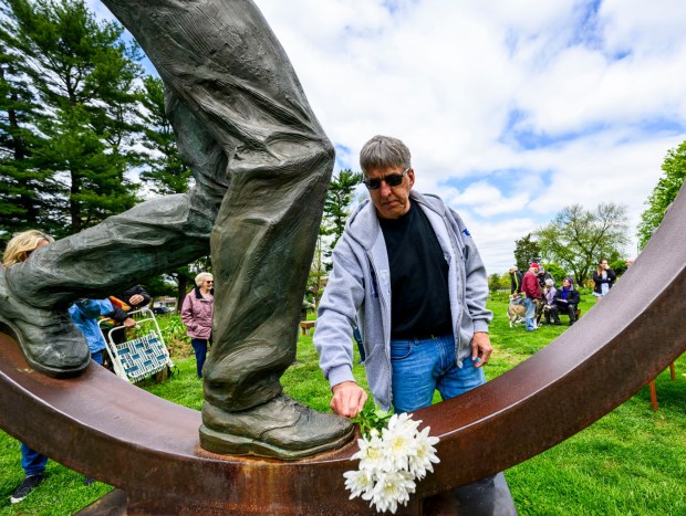 During the 35th annual Lehigh Valley Workers' Memorial Day ceremony Sunday, April 26, 2026, at the Bethlehem Rose Garden, Richard Smith of Pen Argyl places a carnation on the bronze Workers' Memorial sculpture in memory of his father, an employee of the Philadelphia Railroad who died when he was hit by a railroad car on the tracks of Bethlehem Steel in 1978. The ceremony remembered one of the area's bloodiest workplace tragedies, when when two gunmen walked into the First National Bank of Bath and shot five people June 6, 1986, killing three immediately, and a fourth who died years later. Three names will be added this year to the Lehigh Valley Workers' Memorial list, which includes roughly 4,400 workplace facilities since before the Civil War. Added this year are April Lubenetski, 51, who died May 19, 2025, after suffering from occupational cancer as a result of her employment as an Emmaus and Lehigh Township volunteer firefighter; Steven Gill, 36, who died May 21, 2025, when he was hit by an excavator in Weisenberg Township; and James Akins, 57, who died July 29, 2025, after suffering a medical event while installing solar panels on a roof in Allen Township. (April Gamiz/The Morning Call)