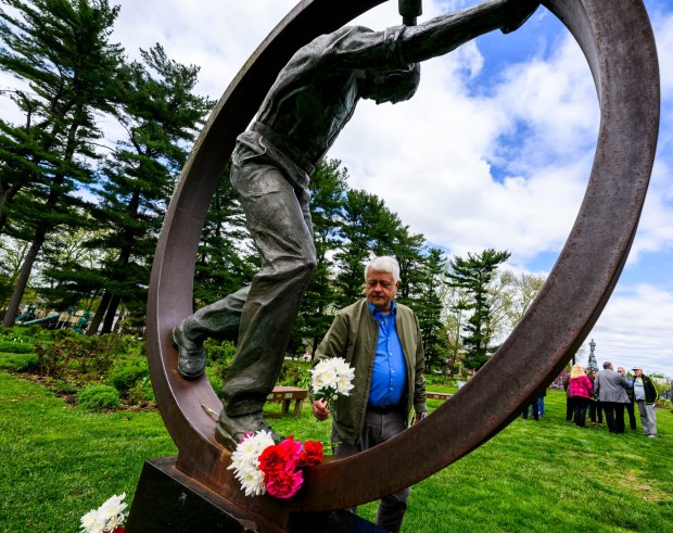 During the 35th annual Lehigh Valley Workers' Memorial Day ceremony Sunday, April 26, 2026, at the Bethlehem Rose Garden, state Rep. Steve Samuelson, D-Northampton, places a carnation on the bronze Workers' Memorial sculpture in memory of workers who died. The ceremony remembered one of the area's bloodiest workplace tragedies, when when two gunmen walked into the First National Bank of Bath and shot five people June 6, 1986, killing three immediately, and a fourth who died years later. Three names will be added this year to the Lehigh Valley Workers' Memorial list, which includes roughly 4,400 workplace facilities since before the Civil War. Added this year are April Lubenetski, 51, who died May 19, 2025, after suffering from occupational cancer as a result of her employment as an Emmaus and Lehigh Township volunteer firefighter; Steven Gill, 36, who died May 21, 2025, when he was hit by an excavator in Weisenberg Township; and James Akins, 57, who died July 29, 2025, after suffering a medical event while installing solar panels on a roof in Allen Township.(April Gamiz/The Morning Call)