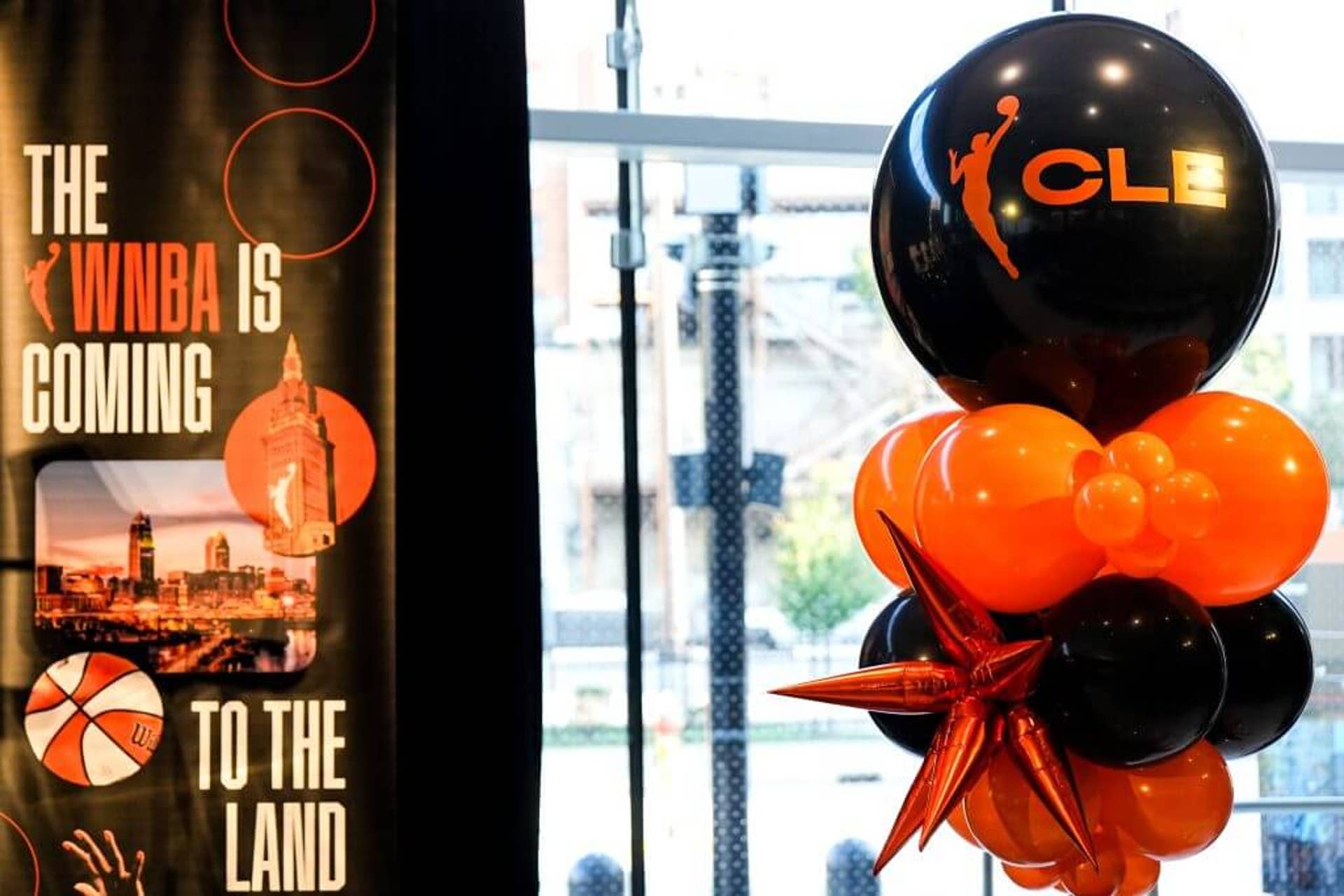 Rocket Arena was host to a WNBA event last September celebrating an expansion team in Cleveland. To the right of the frame are orange and black balloons. To the left is a vertical banner reading, "The WNBA is coming to the land."