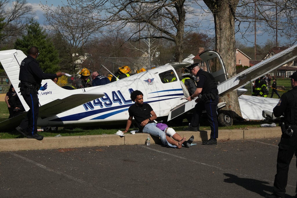 A passenger sits besides the aircraft at the scene after a small airplane made a crash landing