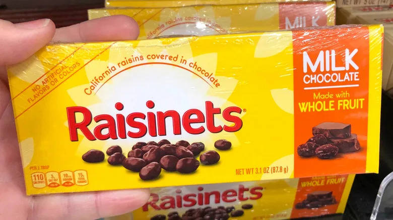 A person holding a box of Raisinets