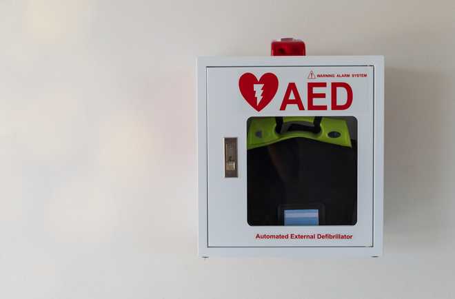 Automated External Defibrillator medical first aid device on white wall.AED box. Automated External Defibrillator medical first aid device on white wall. Portable electronic device that automatically diagnoses the life-threatening cardiac arrest. AED box.