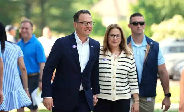 Pennsylvania Gov. Josh Shapiro, accompanied by his wife Lori Shapiro, walks from his polling place in Rydal, Pa., Tuesday, May 19, 2026. (AP Photo/Matt Rourke)
