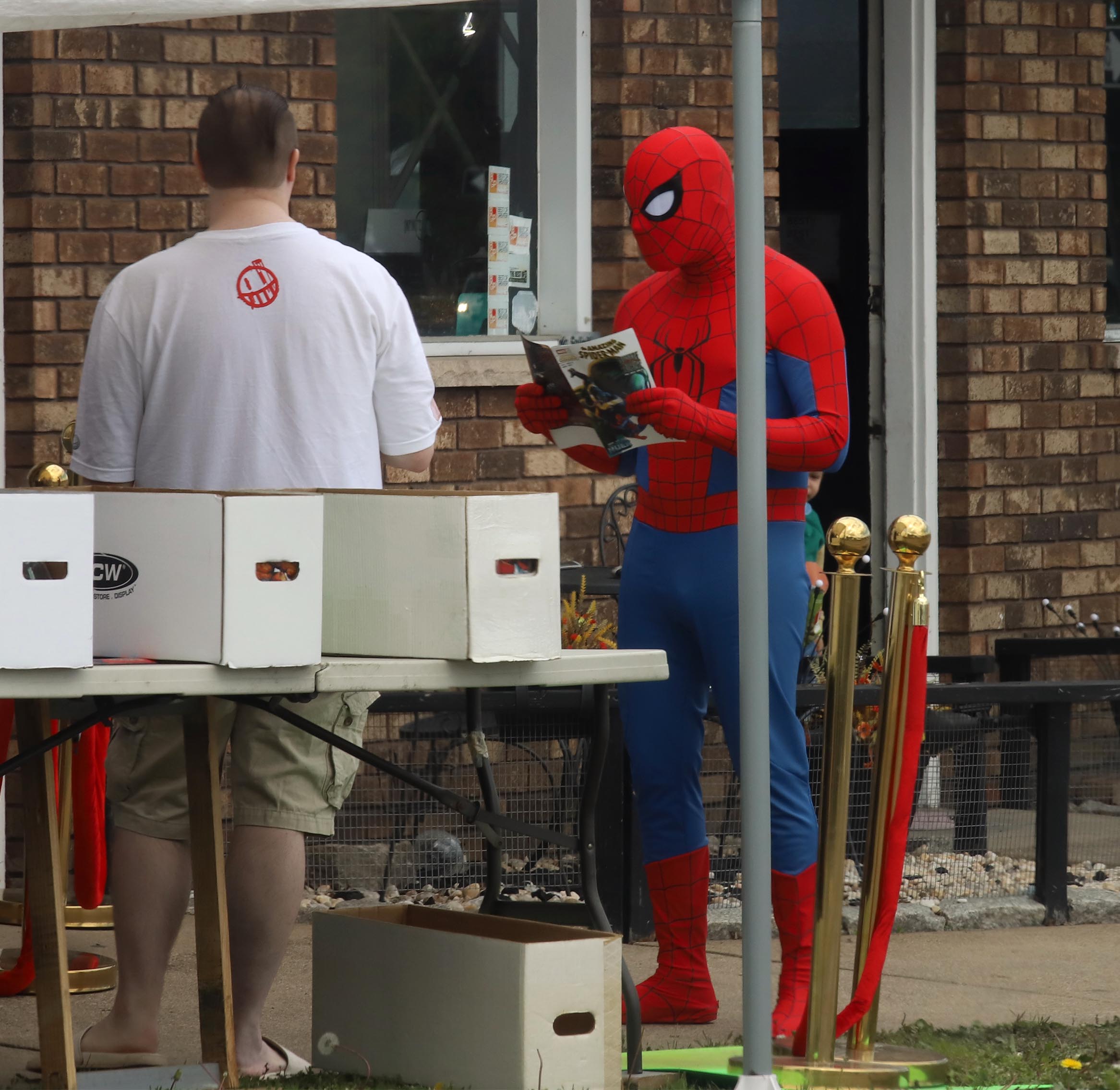 A comic book fan dressed as Spider Man looks over...