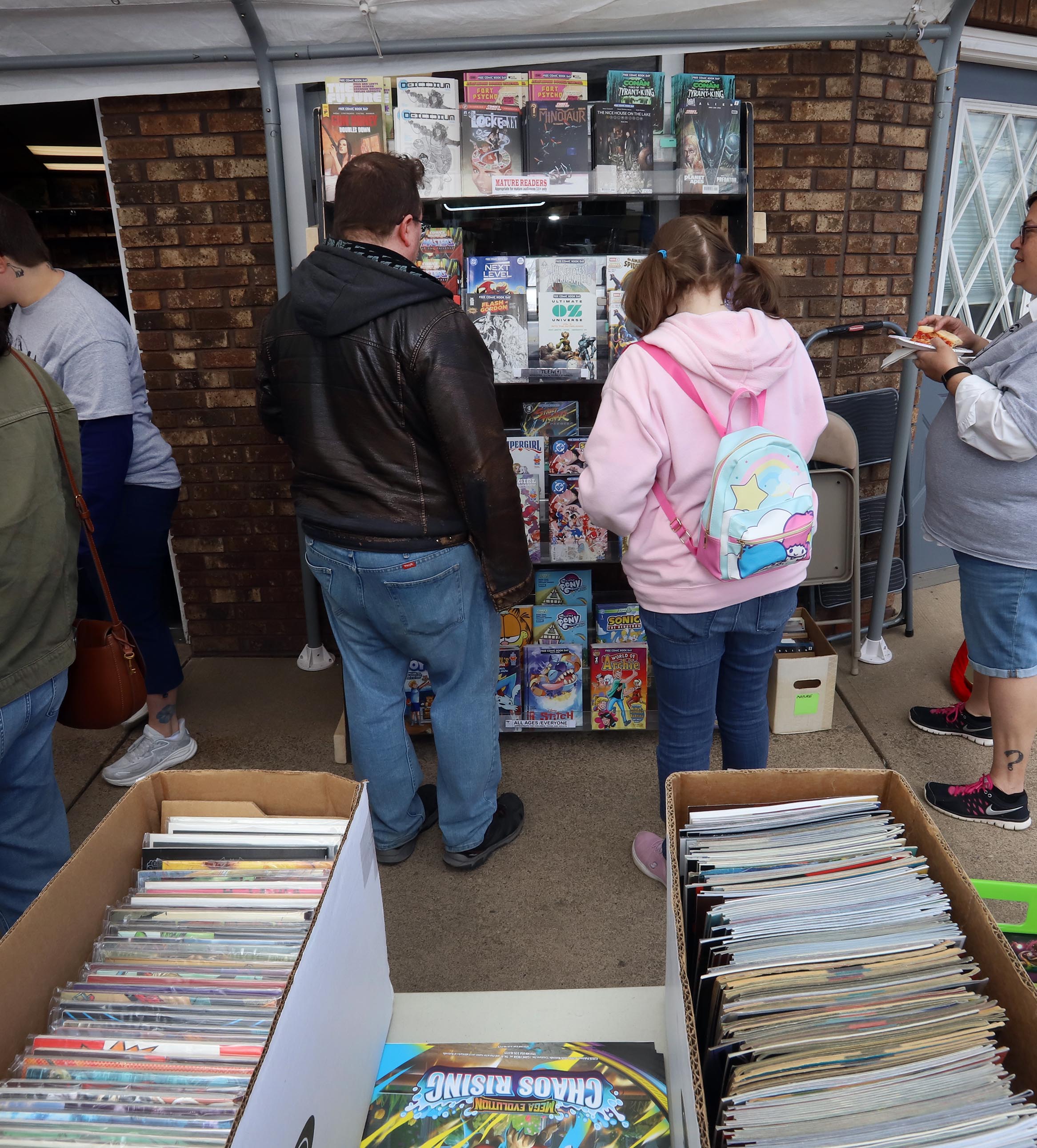 Comic book fans look over some comic books at Rubber...