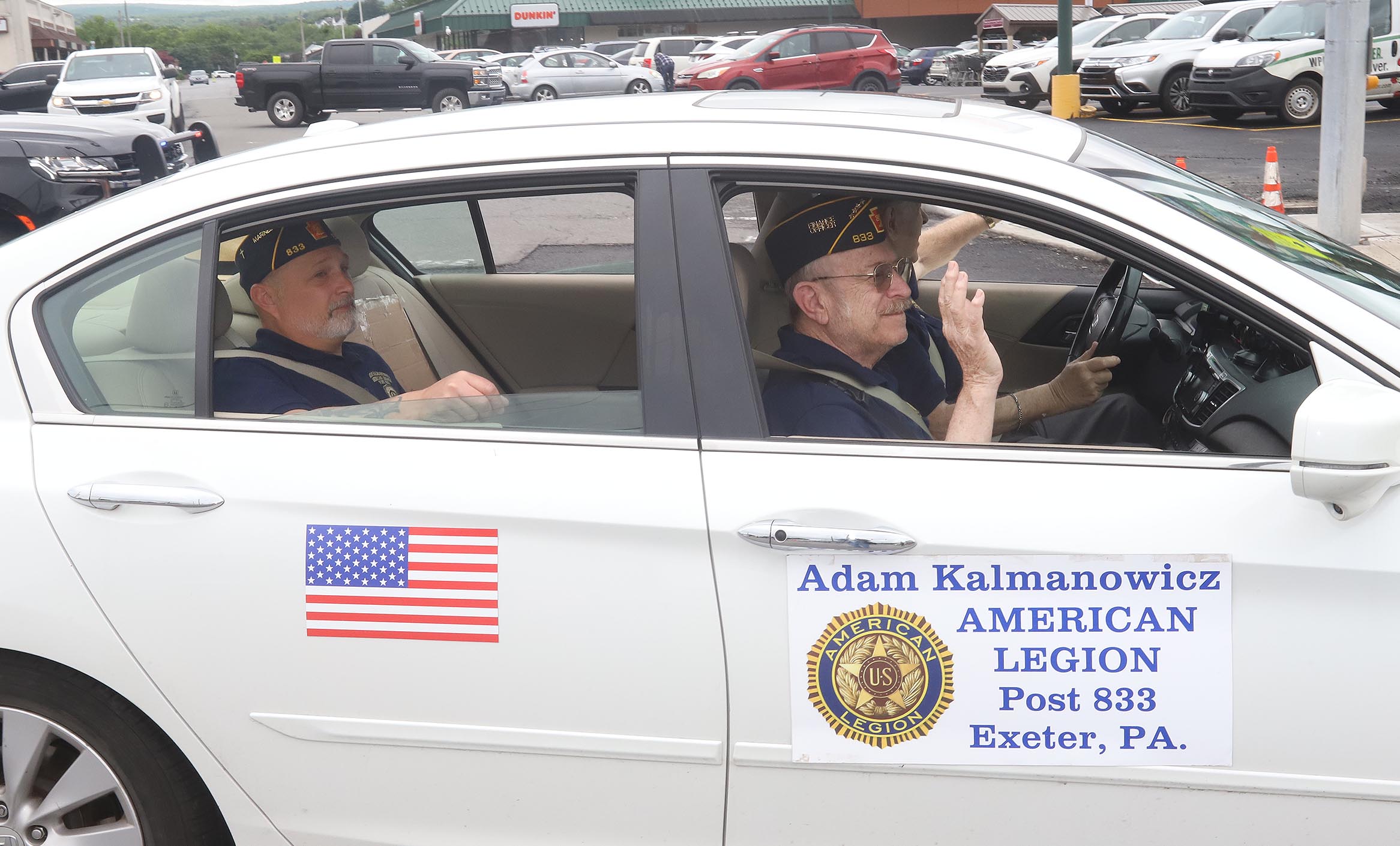Veterans from Exeter wave to the crowds as they make...